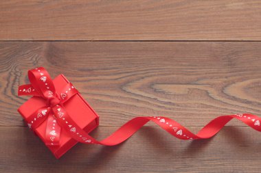 Ahşap bir masa üzerinde bir kurdele ile kırmızı hediye kutusu