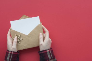 Eller gömlekte, zarfı kırmızı arkaplanda tut. Üst görünüm Noel kartı