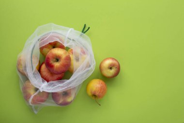 Yeşil arkaplan manzaralı ekolojik poşetteki kırmızı elmalar. Eko-yaşam kavramı