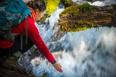 Akan suyun clearwater Falls altında elini tutarak backpacker 