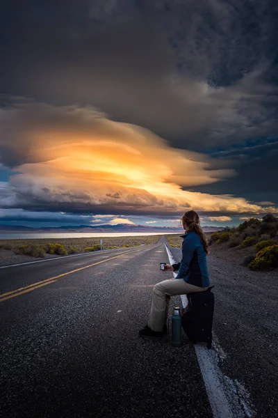 Hitchhiking on a desert road at sunset — Stock Photo, Image