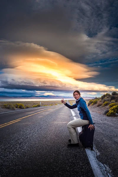 Hitchhiking on a desert road at sunset — Stock Photo, Image