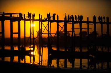 Gün batımında Amarapura 'da U-Bein köprüsündeki insanların silueti. Anne!