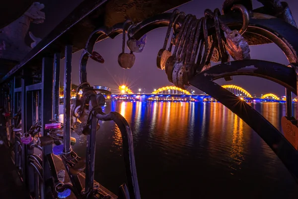 Fechar-se de cadeados fechados são colocados na Ponte do Amor como símbolo do amor. Nigtht vista da ponte do dragão sobre o rio Han em Da Nang, Vietnã — Fotografia de Stock