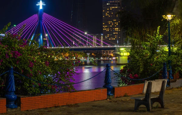 Banc du parc près du pont de la rivière Han illuminé la nuit. Han River. Da Nang, Vietnam — Photo