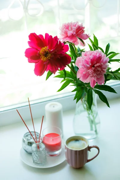 Vase with flowers on the windowsill. A cup of coffee by the wind