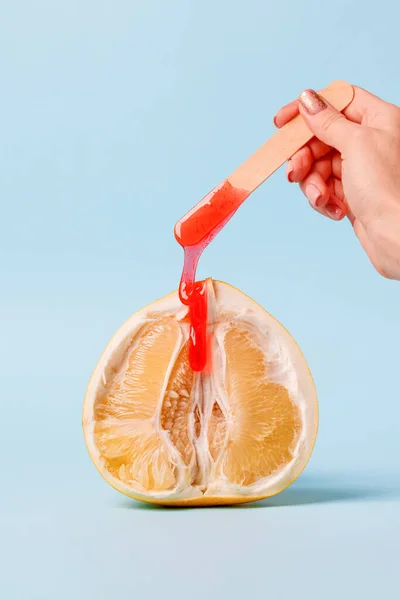 Half pomelo citrus and liquid wax. The concept of intimate depilation - bikini zone, hair removal with hot wax, sugar paste, female beauty, problems of intimate hygiene, minimal closeup