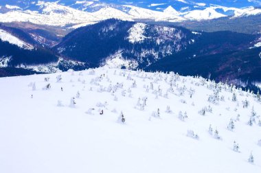 Dağların arka planına karşı dağlık bir alanın karlı yamacı