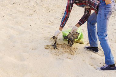 Çöp torbası olan bir adam çöpleri temizliyor.