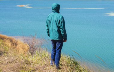 Bir adam bir su deposunun zeminine karşı yamaçta duruyor.