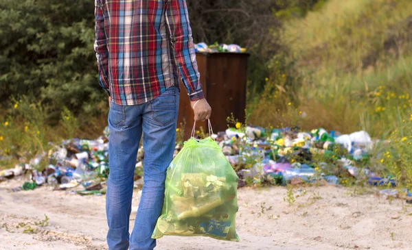 ゴミ袋を持った男がゴミ処理場を掃除し — ストック写真