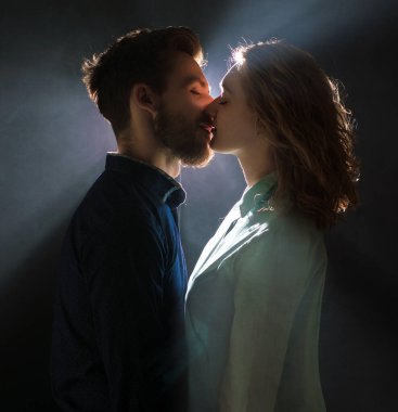 Öpüşme öncesi ışık derelerinde genç ve seksi bir çiftin portresi.