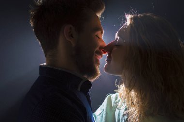 Öpüşme öncesi ışık derelerinde genç ve seksi bir çiftin portresi.