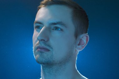 portrait of a guy on a blue background with water drops in the air