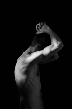 Elleri başının arkasında olan bir adamın dramatik portresi.