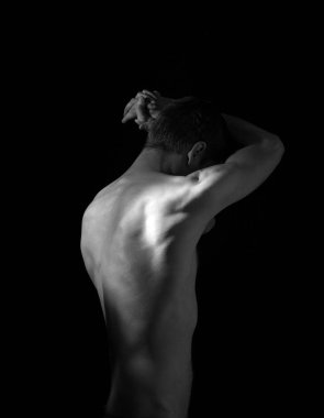 Elleri başının arkasında olan bir adamın dramatik portresi.