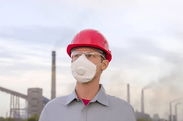 Fabrikanın arka planında kasklı bir adam var.