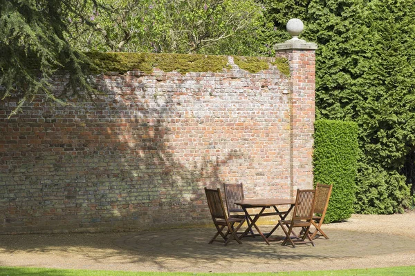 Стол для пикника и стулья в тенистой части сада в окружении — стоковое фото