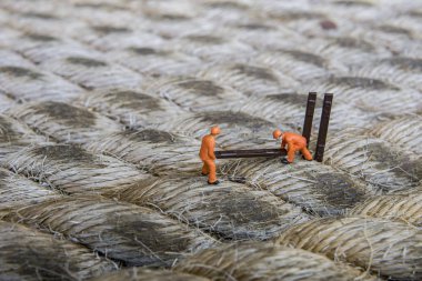 Endüstriyel sektörde çalışan minyatür figür - İp yüzeyi üzerine seçici odaklı inşaat işçileri takım çalışması kavramını kapat.