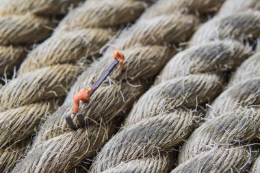 Endüstriyel alanda çalışan minyatür şahıs - İnşaat işçilerinin yakın çekim halat yüzeyi üzerine seçici odaklı takım çalışması görüntüsü.