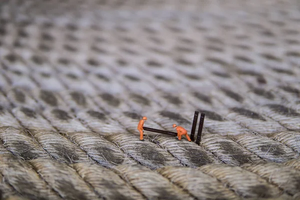 Endüstriyel sektörde çalışan minyatür figür - İp yüzeyi üzerine seçici odaklı inşaat işçileri takım çalışması kavramını kapat.