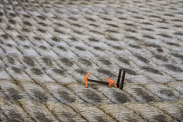 Endüstriyel sektörde çalışan minyatür figür - İp yüzeyi üzerine seçici odaklı inşaat işçileri takım çalışması kavramını kapat.