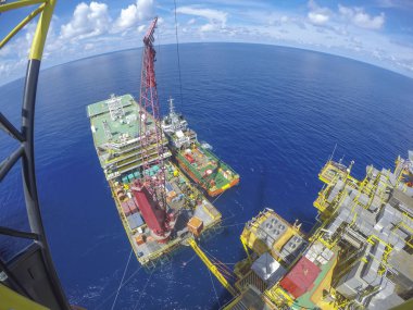 Oil and gas industry. Aerial view of Accommodation Work Barge (AWB) connected with oil and gas platform in the middle of the sea with fish eye effect. clipart
