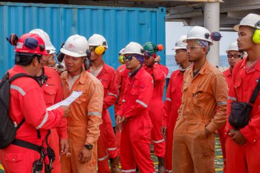 KELANTAN, MALAYSIA - 15 AUG 2019: Petrol ve gaz platformunda çalışmaya başlamadan önce tam teşekküllü kişisel koruma donanımına (PPE) sahip tanımlanamayan açık deniz işçileri kuyruğa girdiler.