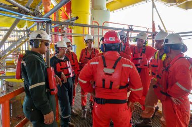 KELANTAN, MALAYSIA - 15 AUG 2019: Petrol ve benzin platformunda çalışmaya başlamadan önce güvenlik brifingi veren kırmızı başlıklı tanımlanamayan güvenlik görevlisi.