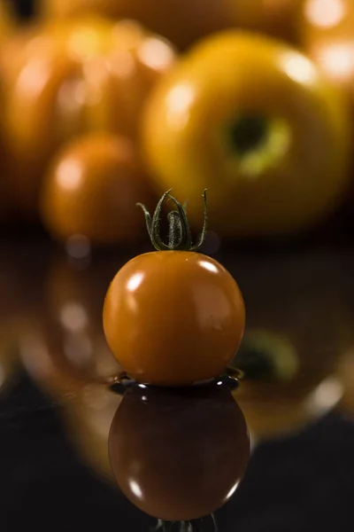 Gelbe Tomaten auf schwarzem Hintergrund, Wassertropfen, Spiegel — Stockfoto
