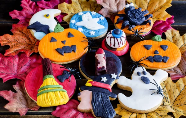 Biscotti di Halloween fatti a mano con glassa sul fogliame autunnale — Foto Stock