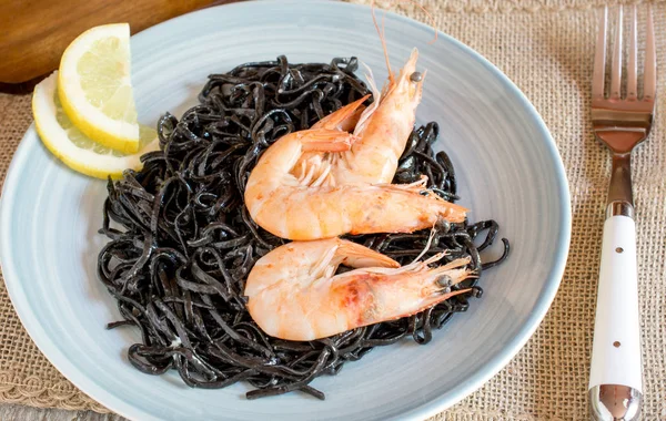 Shrimps with black seaweed on plate with lemon — Stock Photo, Image