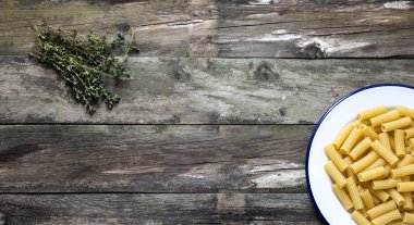 Pişmemiş makarna rustik ahşap bir masa üzerinde bir tabakta servis,