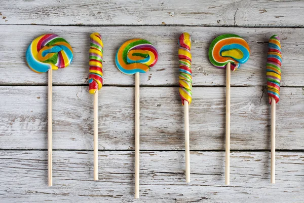 Several colorful lollipops on wooden board — Stock Photo, Image