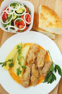 Patates ve sebze salatası ile domuz eti rulo.