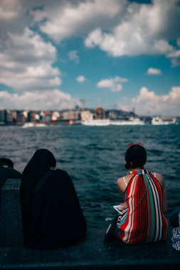 Nehrin kenarında oturan iki kişi.