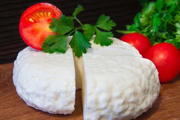 Young oak cheese cutting Board with tomatoes and parsley. Mozarella for pizzas and salads. — Stock Photo, Image