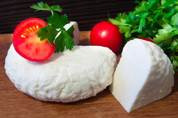 Young oak cheese cutting Board with tomatoes and parsley. Mozarella for pizzas and salads. — Stock Photo, Image