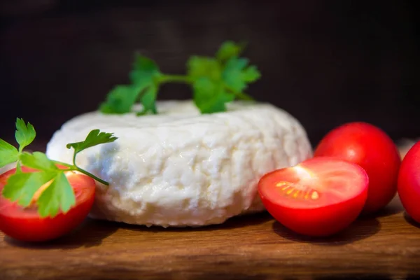 Young oak cheese cutting Board with tomatoes and parsley. Mozarella for pizzas and salads. — Stock Photo, Image