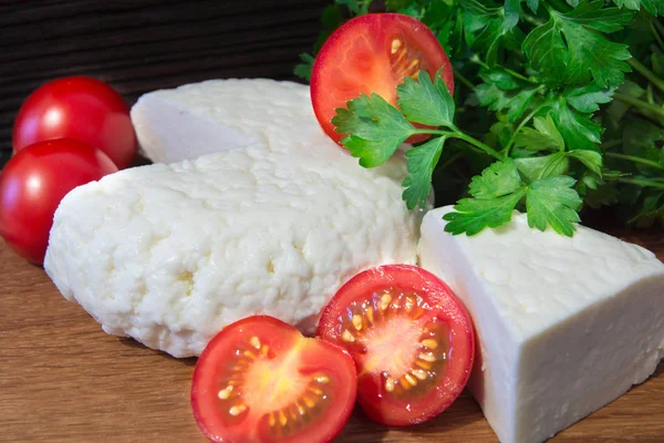 Young oak cheese cutting Board with tomatoes and parsley. Mozarella for pizzas and salads. — Stock Photo, Image