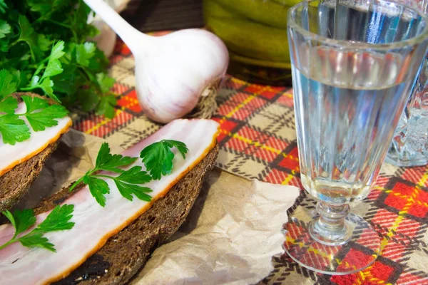 Traditional Ukrainian and Russian appetizer when dining. Food when drinking alcohol. Vodka and sandwiches with bacon, garlic and pickles. — Stock Image Traditional Ukrainian and Russian appetizer when dining. Food when drinking alcohol. Vodka and sandwiches with bacon, garlic and pickles. Royalty Free Stock Images