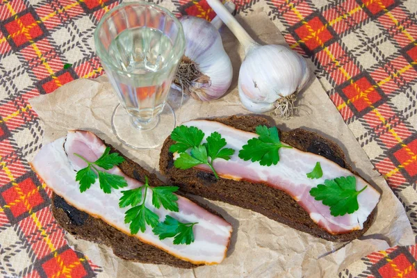 Traditional Ukrainian and Russian appetizer when dining. Food when drinking alcohol. Vodka and sandwiches with bacon, garlic and pickles. — Stock Image Traditional Ukrainian and Russian appetizer when dining. Food when drinking alcohol. Vodka and sandwiches with bacon, garlic and pickles. Stock Picture