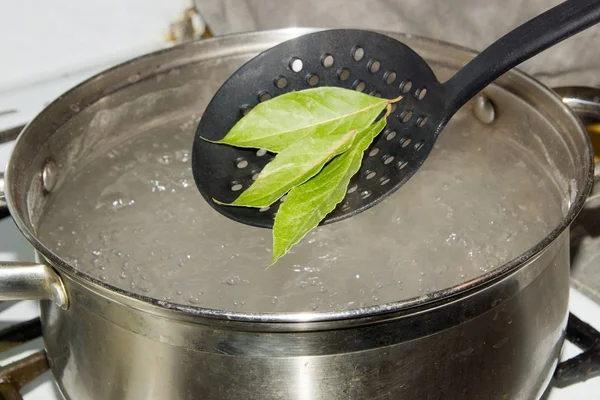The pot of boiling water, which omit the Bay leaves, give the dish a savory aroma and taste. — Stock Photo, Image