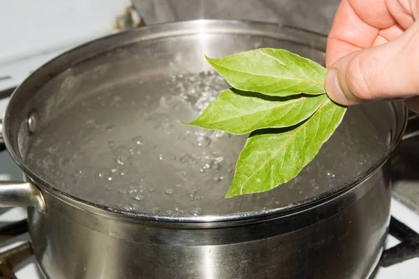 La olla de agua hirviendo, que omiten las hojas de la bahía, dan al plato un aroma y sabor salados . — Foto de Stock