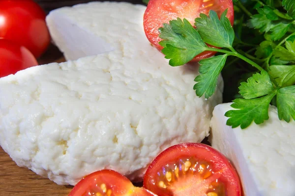 Fresh cheese with excellent taste and aroma. Cheese on wooden cutting Board with tomatoes and fresh herbs. — Stock Photo, Image