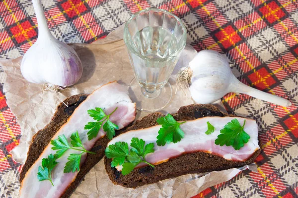 Aperitivo tradicional ucraniano e russo ao jantar. Comida ao beber álcool. Vodka e sanduíches com bacon, alho e picles . — Fotografia de Stock