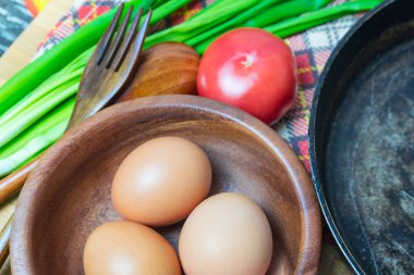 Eski bir tavada tavuk yumurta pişirme için malzemeler hazırlanması.
