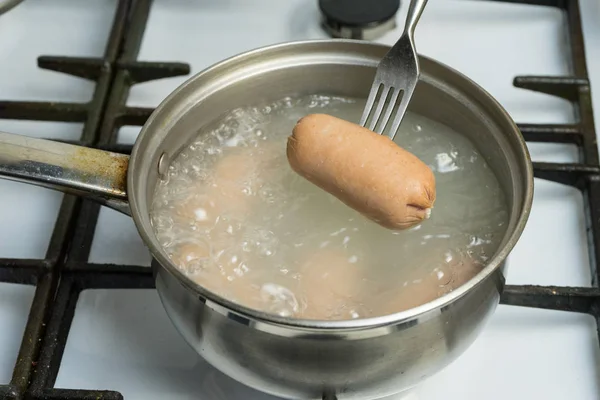 水を沸騰の鍋から抜け出すにソーセージをゆでた ホット ソーセージはフォークです ガスコンロの上で家庭料理 — ストック写真
