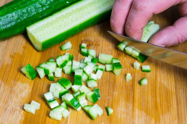 Farklı yemekler hazırlamak için taze bir salatalık kesmek.
