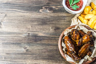 Susam ile güzel kokulu ve keskin soslu tavuk kanatları. Bir bardak taze soğuk bira ve taze domates ve otlar rustik domates soslu patates kızartması